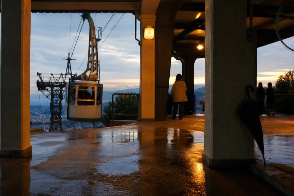 A cable car cabin arriving at an open-air mountain station platform at dusk, no text, no logos, no people