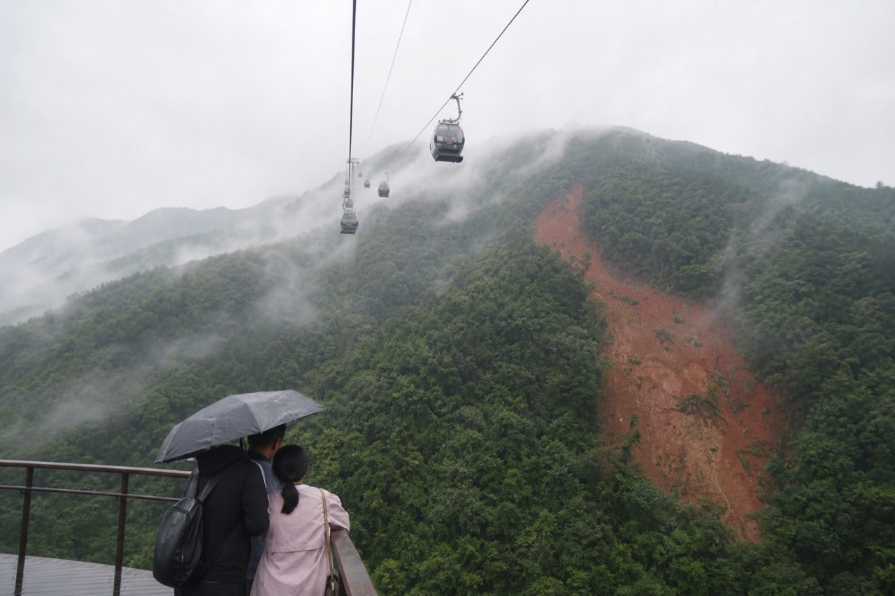 Aerial cable car cabins travelling over green forested hills above Taipei, no text, no logos, no people