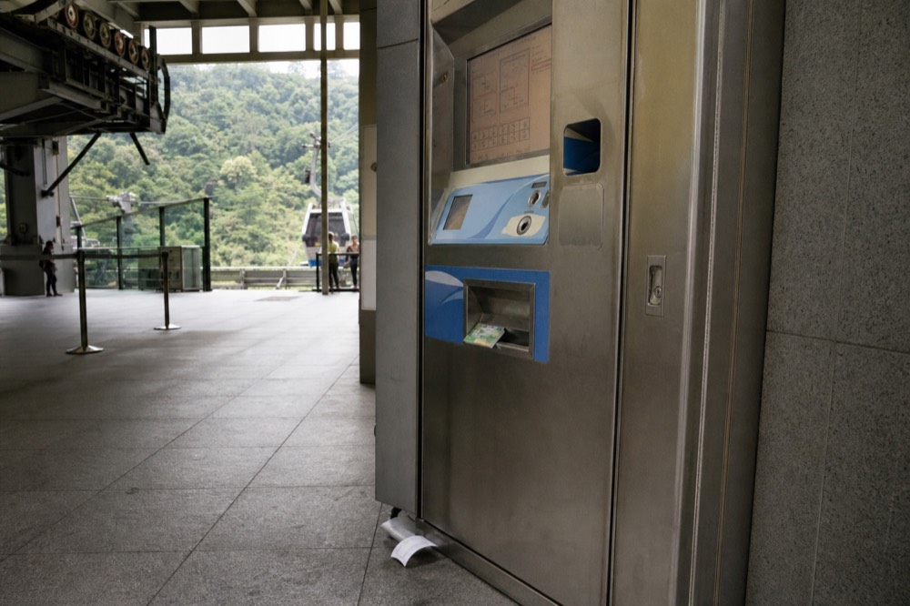 Fare gates at a Taipei cable car station with passengers tapping contactless cards, no text, no logos, no people