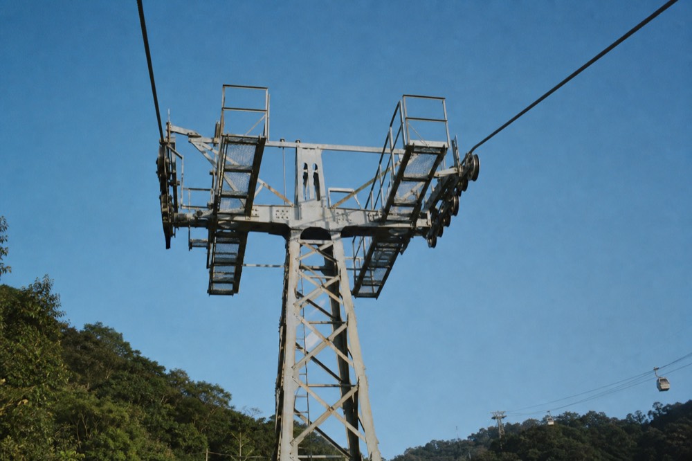 Steel cable and sheave wheels on a gondola tower against the sky, no text, no logos, no people