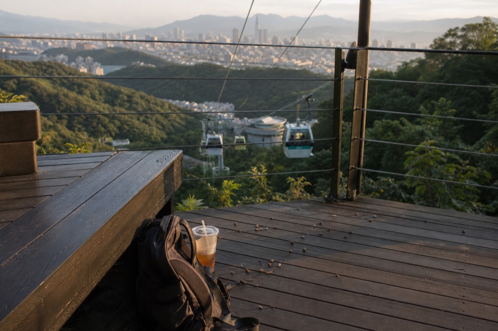 A long cable car line stretching across a forested hillside toward Taipei in the distance, no text, no logos, no people
