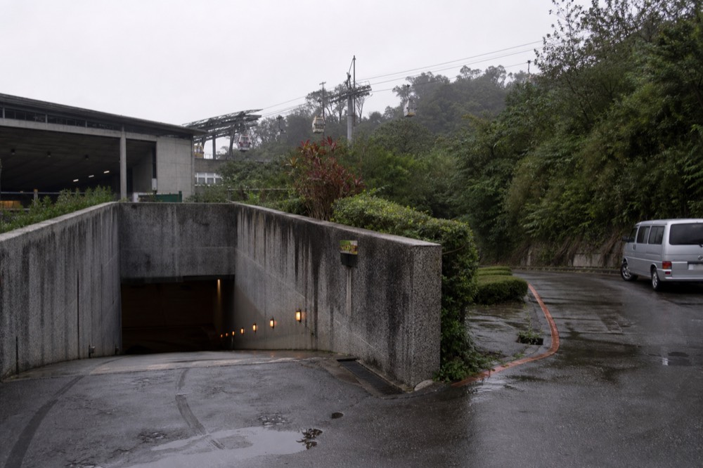 An underground car park entrance beside a green hillside station, no text, no logos, no people