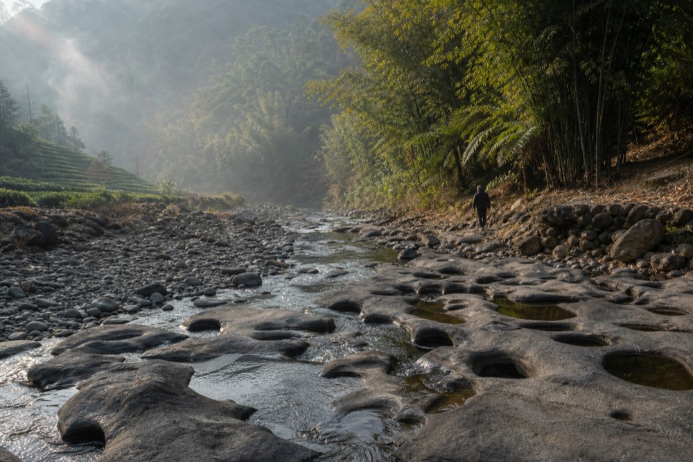A mountain streambed with round potholes worn into dark igneous rock, no text, no logos, no people
