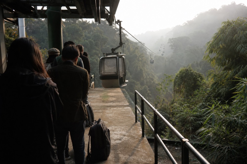 Short queue of visitors on a station platform beside arriving cabins in early morning, no text, no logos, no people