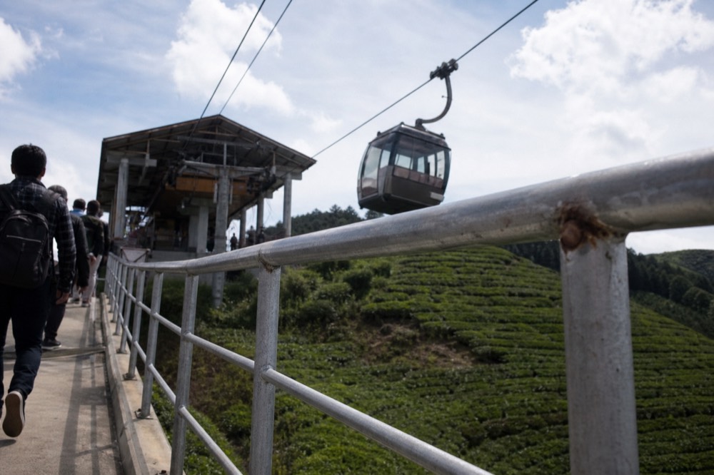 A cable car cabin arriving at a hilltop station above green slopes, no text, no logos, no people