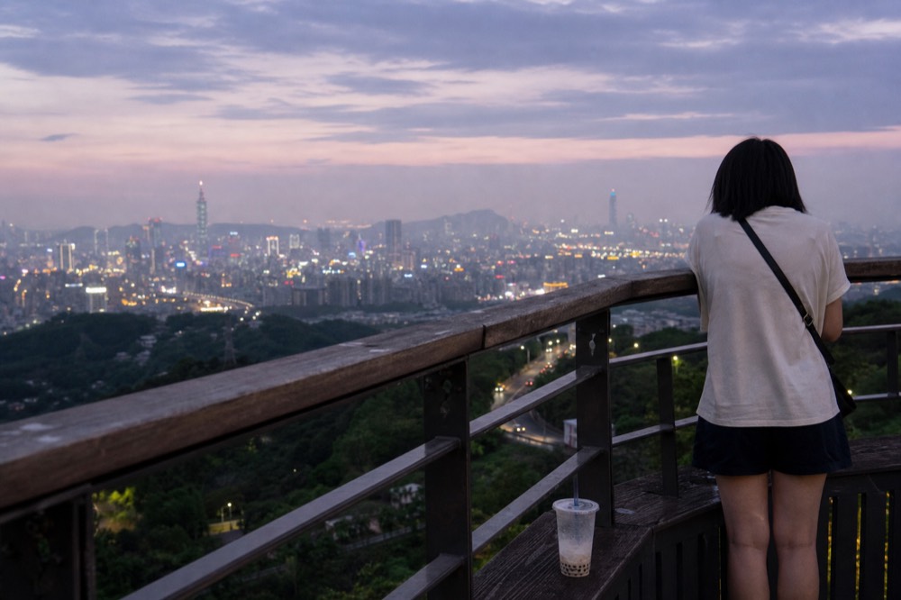 A viewpoint deck above Taipei at dusk seen from the mountain, no text, no logos, no people