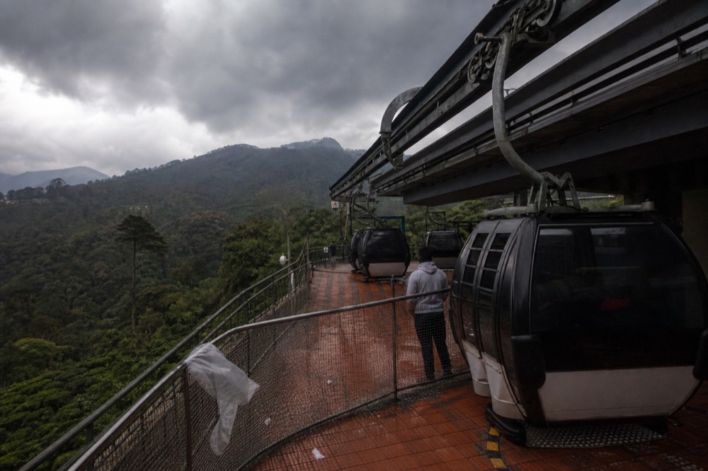 Gondola cabins stationary at a station platform under grey storm clouds, no text, no logos, no people