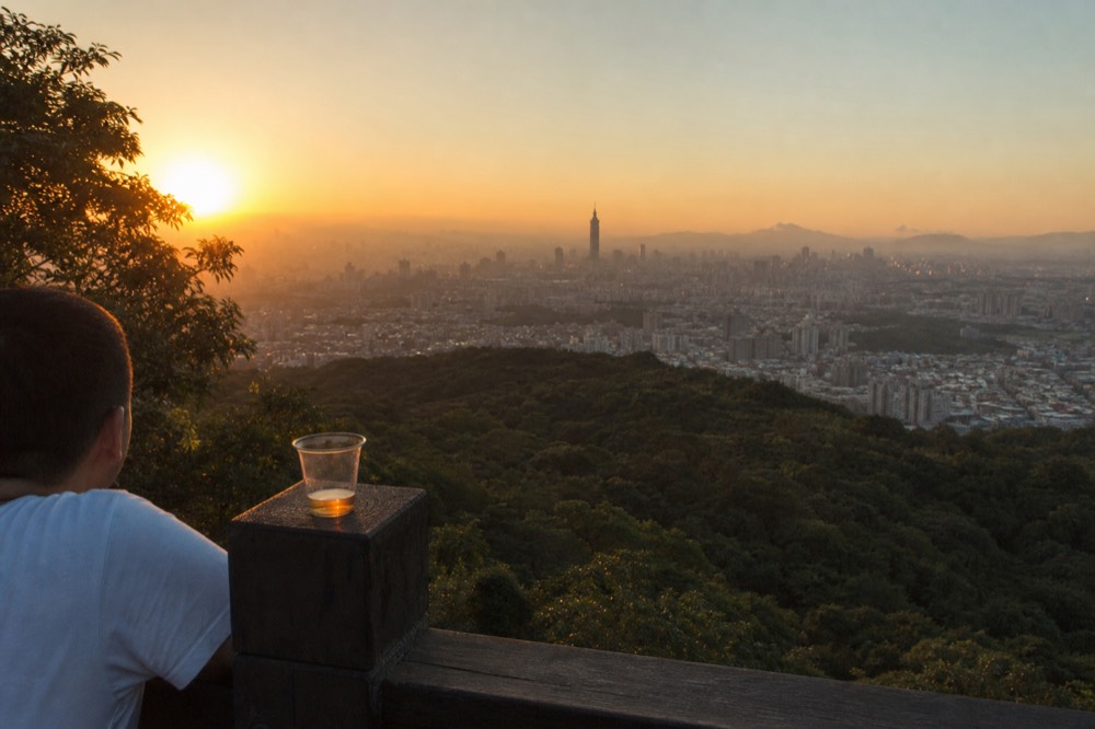 Sunset light over the Taipei basin seen from a Maokong hillside viewpoint, no text, no logos, no people