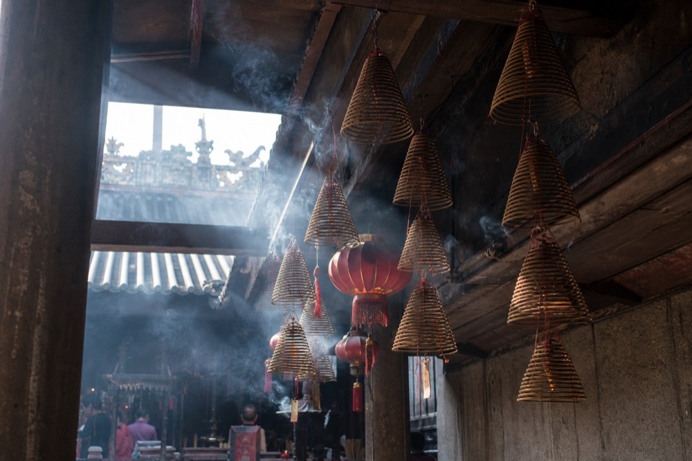 Incense coils and red lanterns hanging under a temple eave, no text, no logos, no people