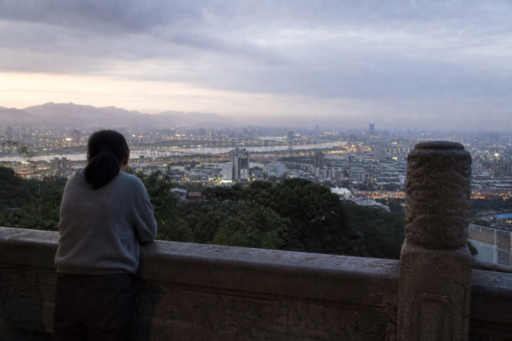 Wide view over the Taipei basin from a temple terrace at dusk, no text, no logos, no people