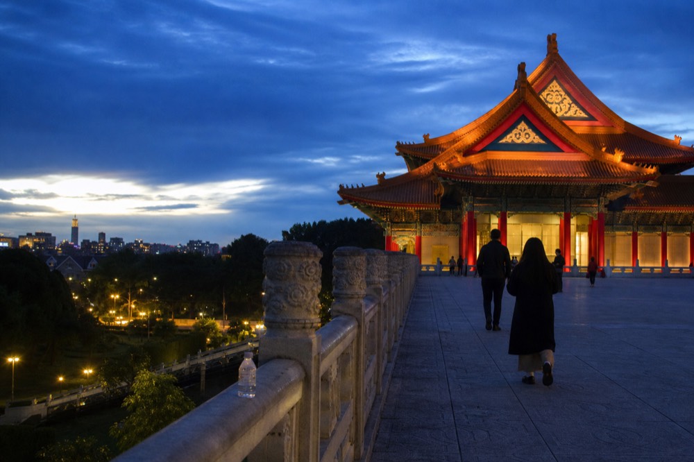 Evening view of temple halls lit warmly against a darkening sky over Taipei, no text, no logos, no people